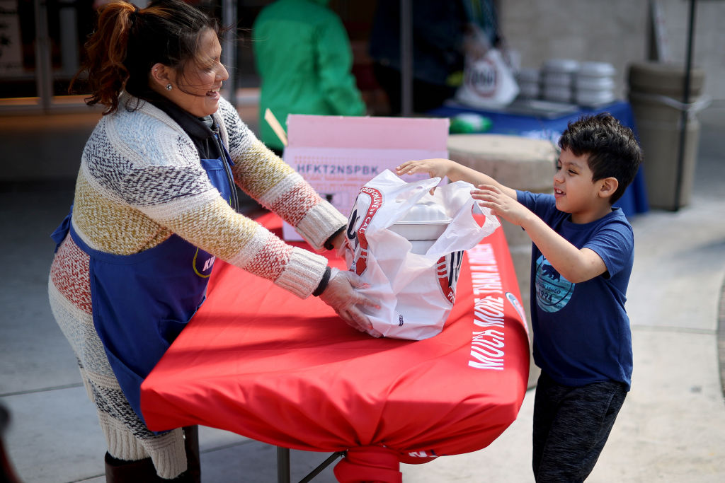 GAITHERSBURG, MARYLAND - APRIL 02: Silver Diner senior marketing manager Cindy Sabana (L) helps hand out 400 free meals outside the restaurant during the coronavirus pandemic April 02, 2020 in Gaithersburg, Maryland. With thousands of children missing meals due to the COVID-19 pandemic closing schools, Silver Diner is partnering with Real Food for Kids to provide 400 free meals a day to families in need beginning at 2pm every weekday.  (Photo by Chip Somodevilla/Getty Images)